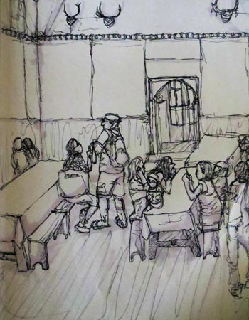 Tourists sit on benches at tables in a tall room lined with racks of atlers.