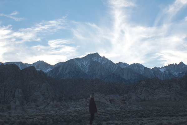 A young, college age free spirit looking over rocky hills and then Mt. Whitney in the distance.