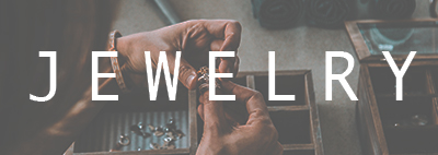 Hand holding rings with white letters saying jewelry