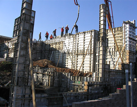 An image of a pour crew using a boom pump to pour a massive stem wall for an out of level project