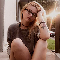 Portrait picture of myself sitting down outside with the sun shining behind