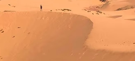 Distant silhoutte of Jennifer Rose standing on the Coral Pink Sand Dunes in Utah, USA. 