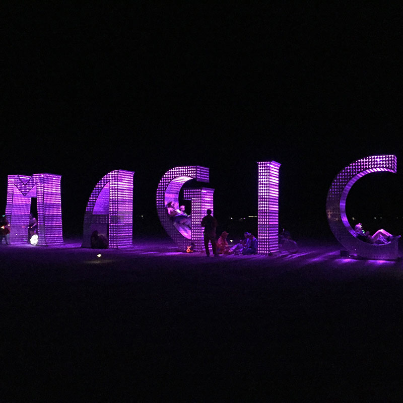 Giant Purple letters spaced out to say MAGIC with people sitting inside the letters 