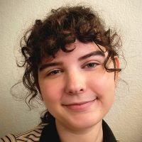 A girl with brown, curly hair smiling at the camera.