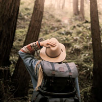 A woman looks up into the tree while hiking.
