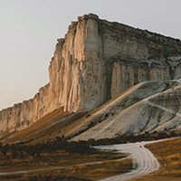 A large rock formation with a dirt road leading to it.