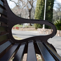 A close-up of the armrest on a metallic bench.