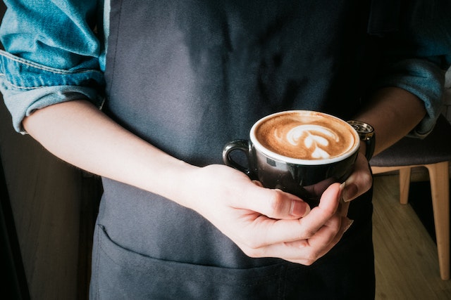 A picture of hands cradling a latte with a design in the drink
